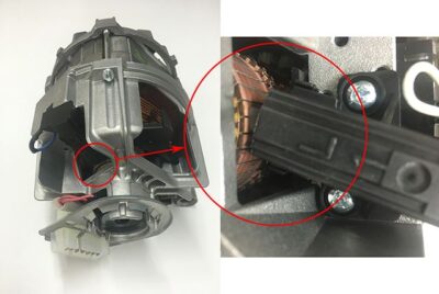 Carbon brushes contacting motor armature in washing machine motor assembly